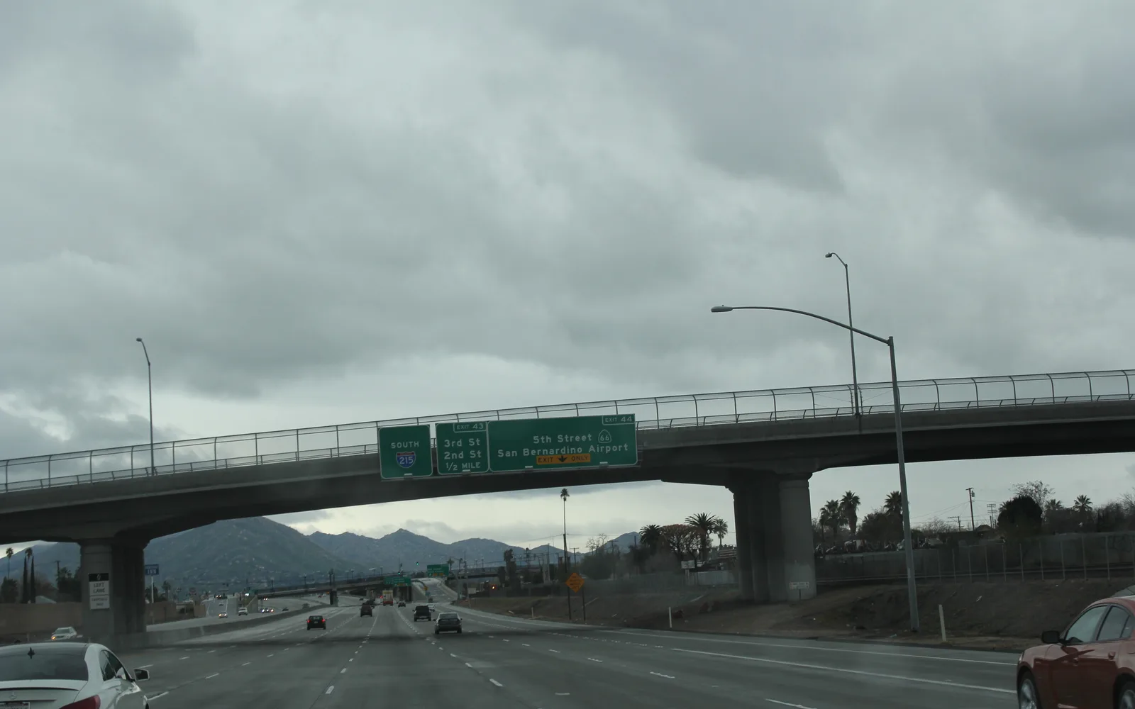 An elevated view of Interstate 215 showing multiple lanes, bridge overpass, and surrounding Southern California landscape